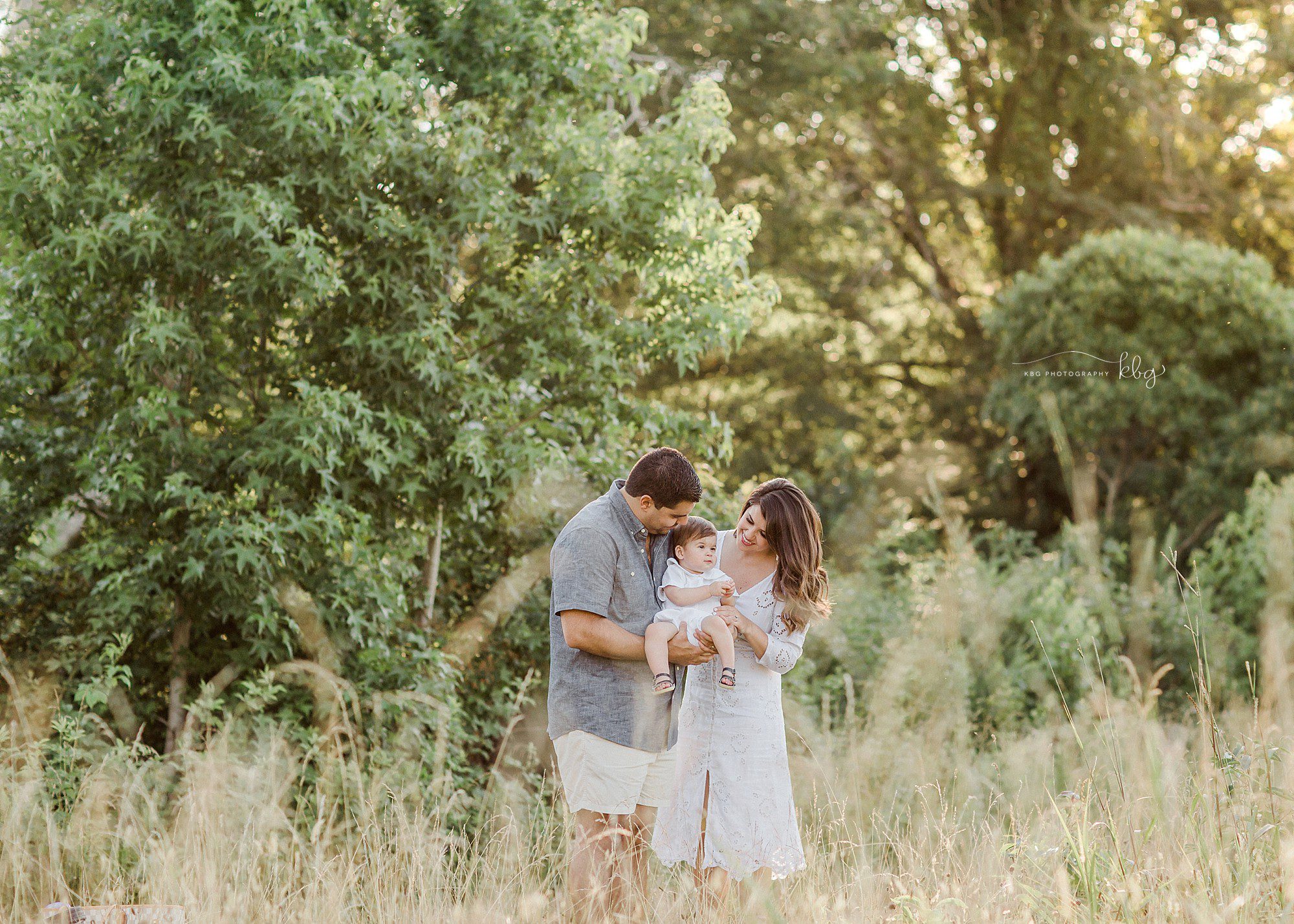 atlanta family photographer - mom and dad cuddling with baby boy in field