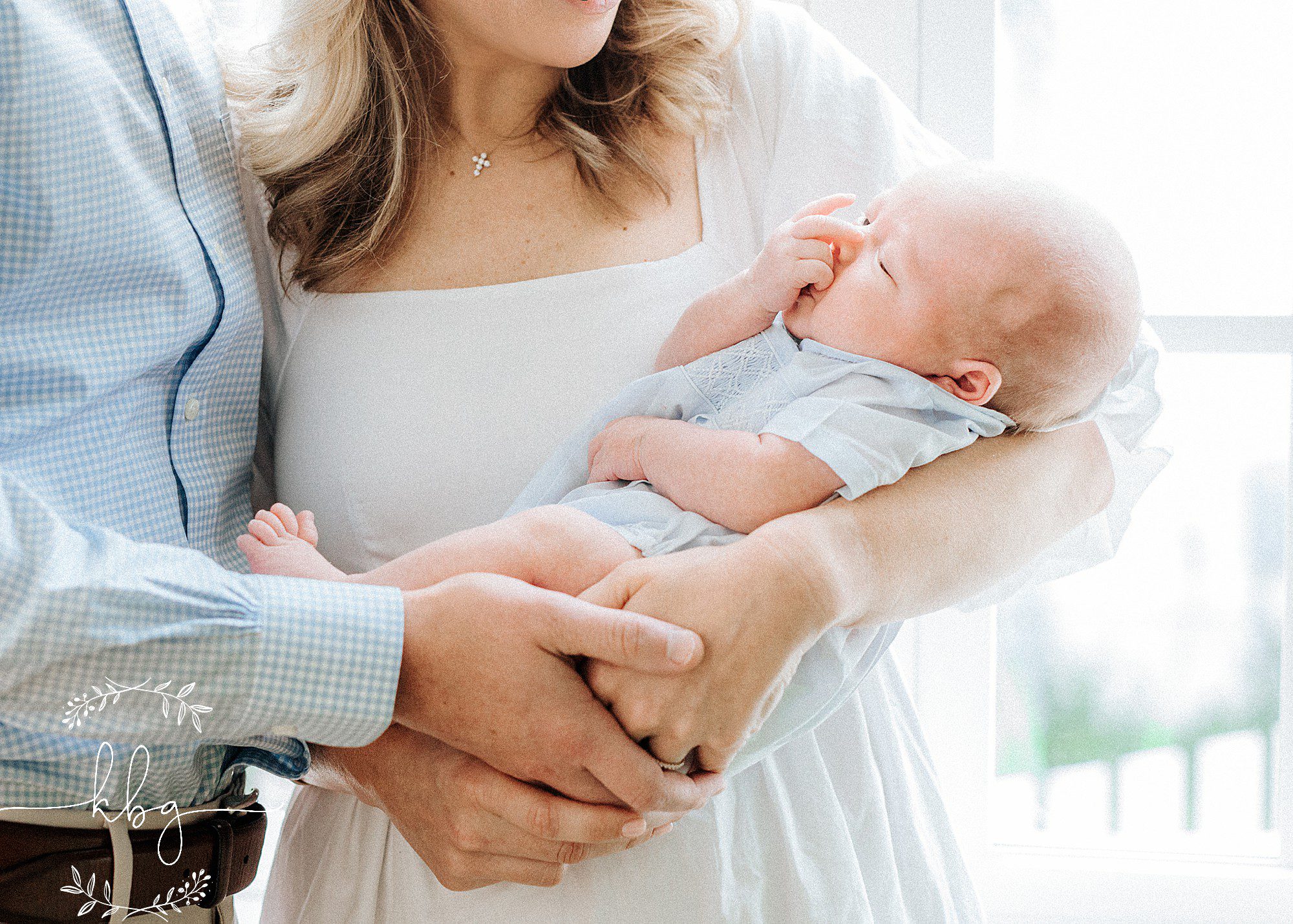 mom and dad holding new baby in front of window - brookhaven newborn photographer
