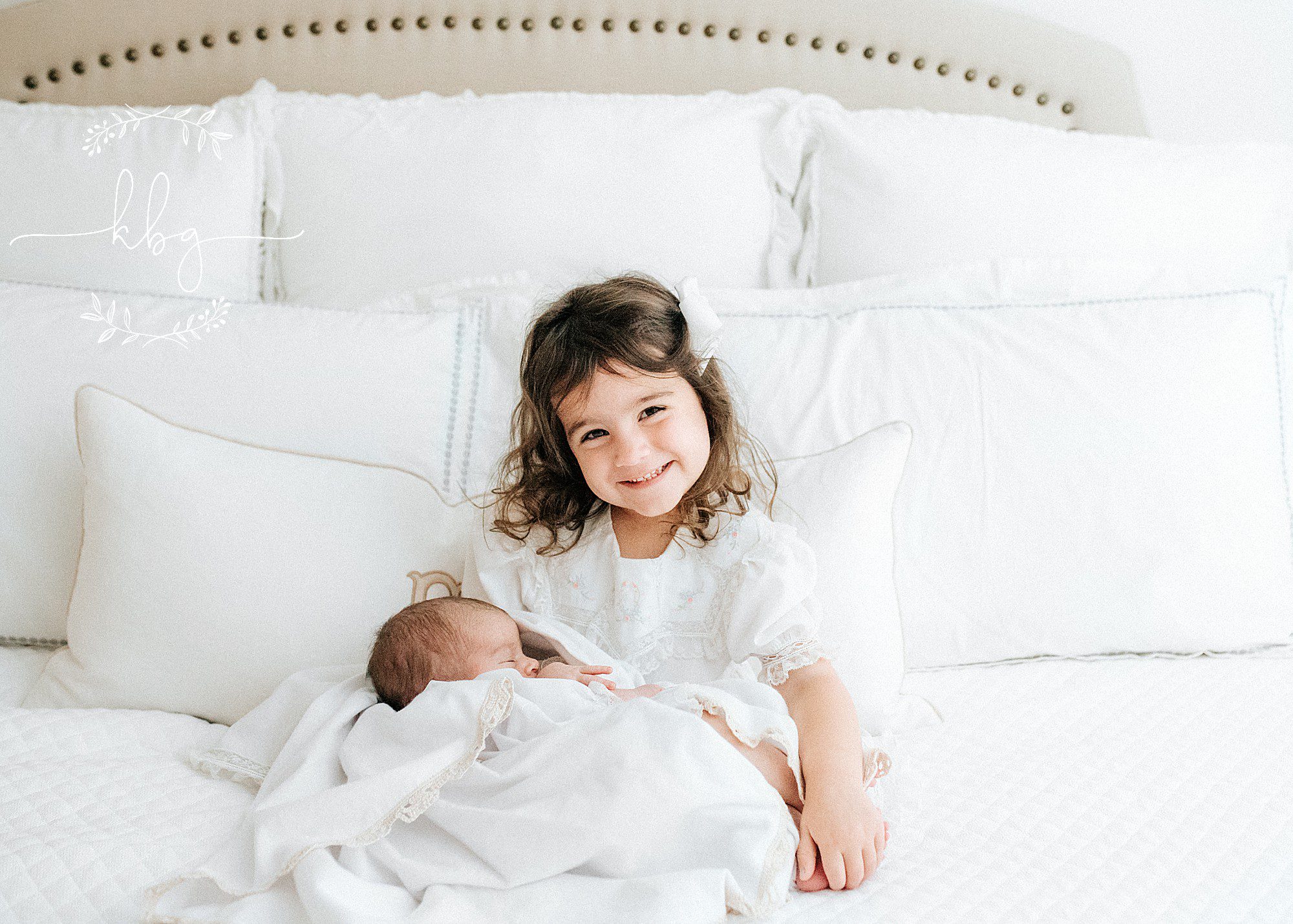big sister holding baby sister on mom and dad's bed - atlanta family photographer